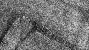 Texture of grey fabric with soft fibers and frayed edges, perfect for clothing or upholstery."