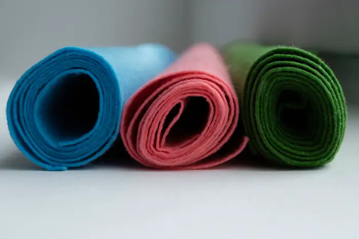 "Rolled colorful sports fabric mats in blue, pink, and green, ideal for activewear and sportswear materials."