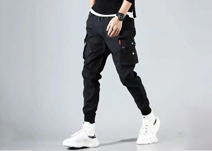 Trendy men's black jogger pants featuring cargo pockets, paired with white sneakers for a stylish streetwear look.
