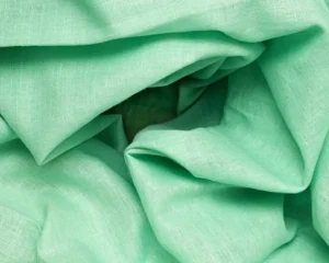 Textured green fabric with soft creases, ideal for creating lightweight and breathable garments