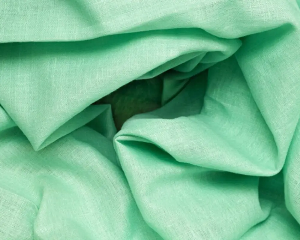 Textured green fabric with soft creases, ideal for creating lightweight and breathable garments