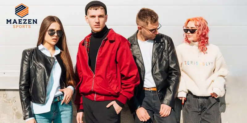 A group of four friends wearing stylish leather jackets, with one in a red jacket and another in a white hoodie, posing in front of a white background.

