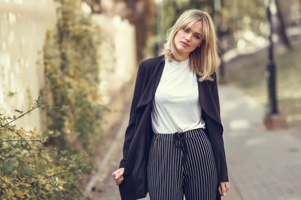 "Woman wearing a long black cardigan jacket paired with striped pants, ideal for a casual chic look."