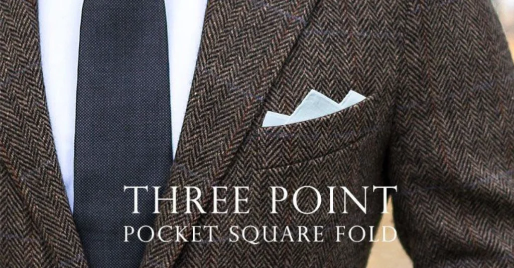 A stylish three-point pocket square fold displayed in the breast pocket of a herringbone suit