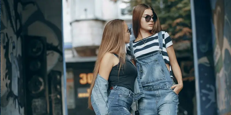 "Two women dressed in stylish denim overalls, showcasing trendy pant options for the guide."