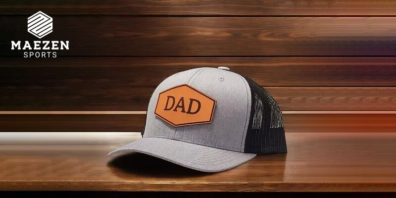 A grey "Dad" hat with a bold orange patch reading "DAD" displayed on a wooden surface .