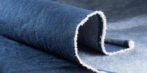 Close-up of a rolled denim fabric showcasing its texture for pant guide blog."