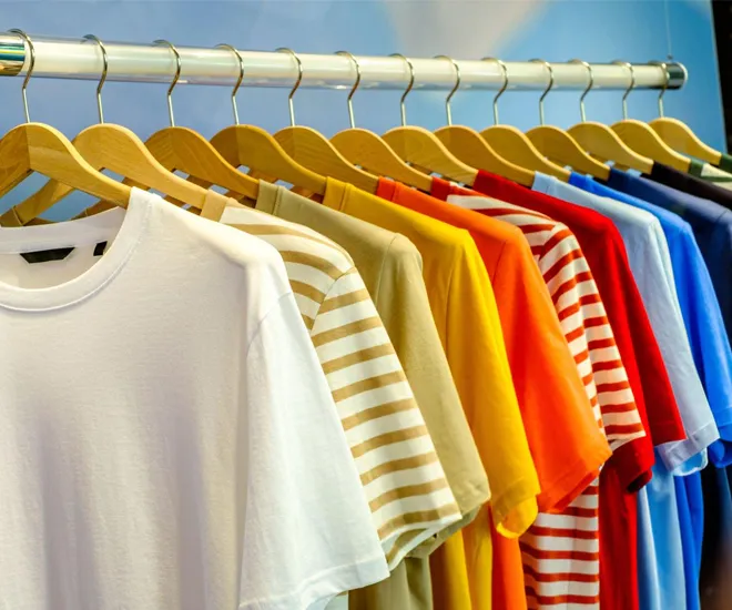 A variety of colorful t-shirts neatly displayed on hangers in a retail store, offering a wide selection of vibrant and casual styles for all seasons."
