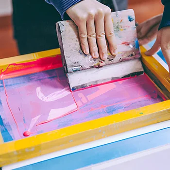 Hand pressing ink onto a screen in the screen printing process to create vibrant prints.