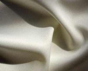 “Close-up of soft, cream-colored fabric with a smooth, silky texture and gentle folds.”